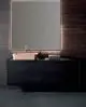 Waschtisch mit schwarzem Unterbau, einer braunen Schüssel oben, einer Chrom-Armatur von Ideal Standard und einem beleuchteten Spiegel im Hintergrund.